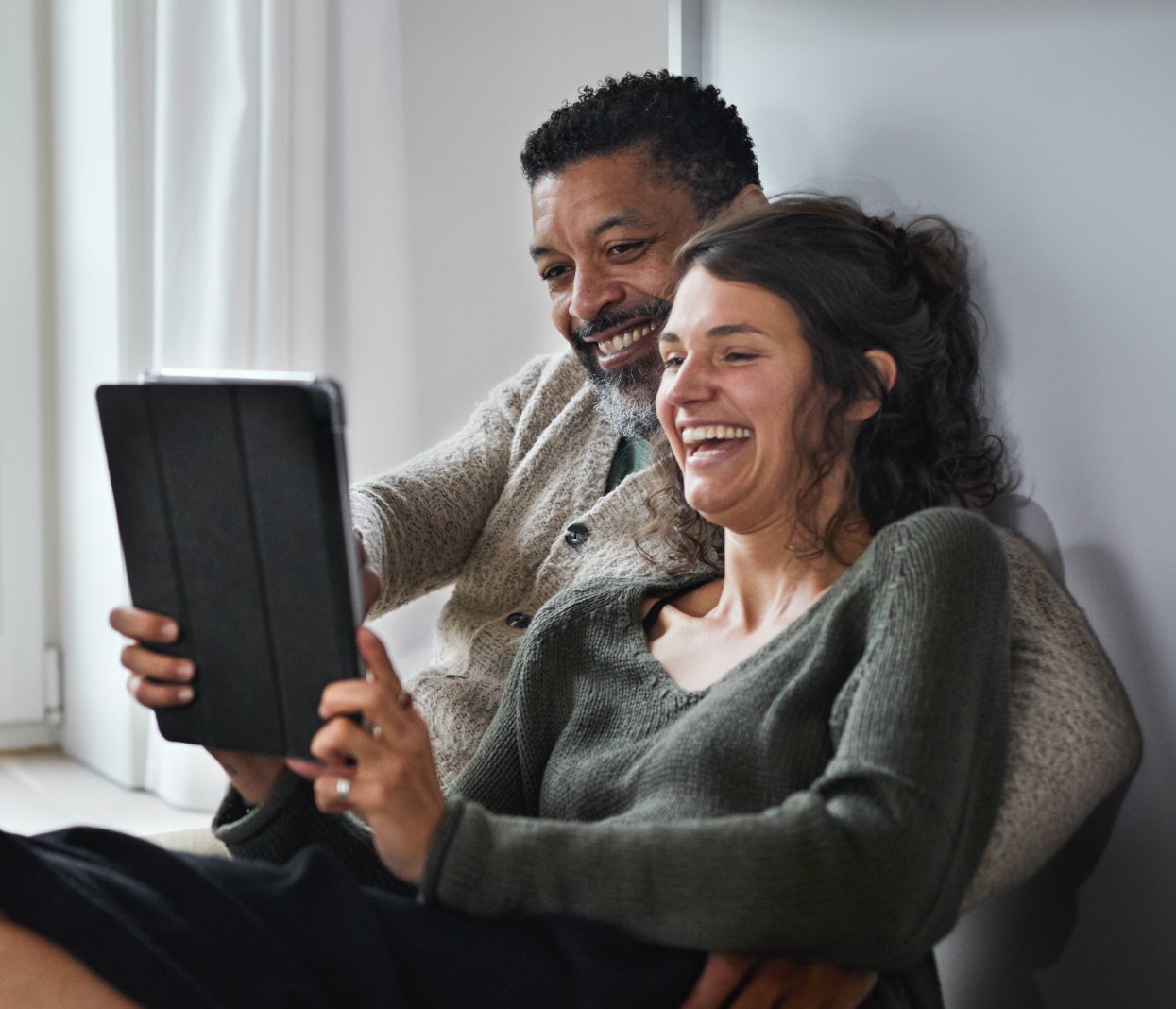 Couple laughing while streaming video on their tablet