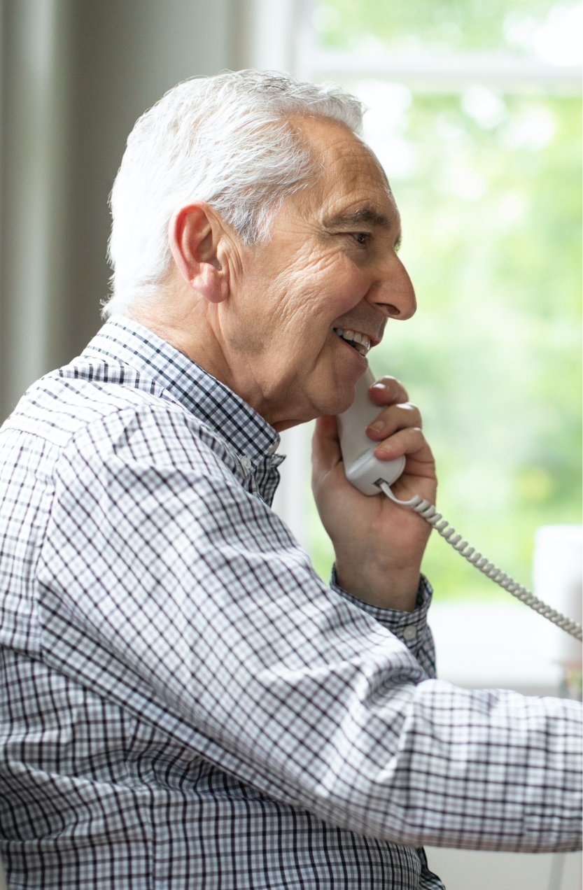 Old man talking on a corded phone at home