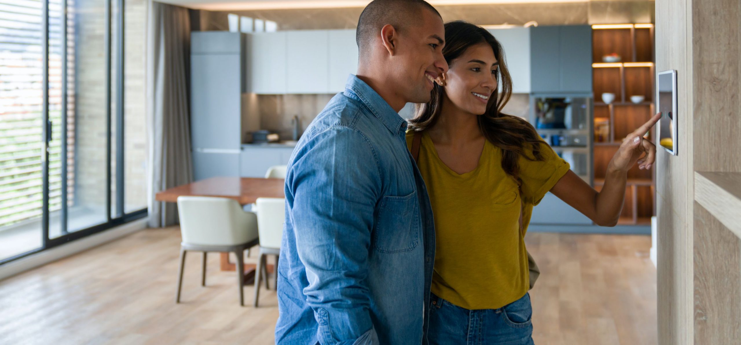 Young couple in their home adjusting the security controls on a touch screen panel