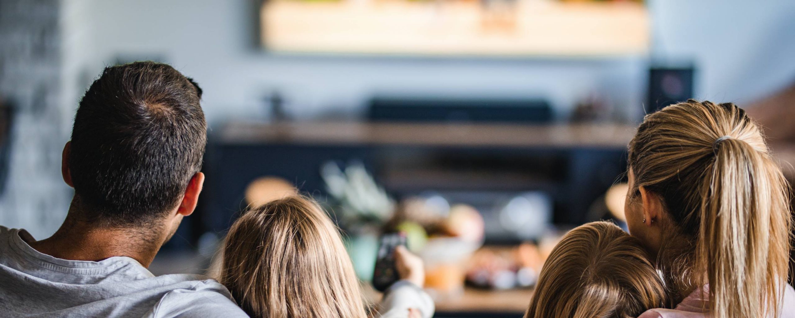 Family sitting on a couch watching tv and changing channels