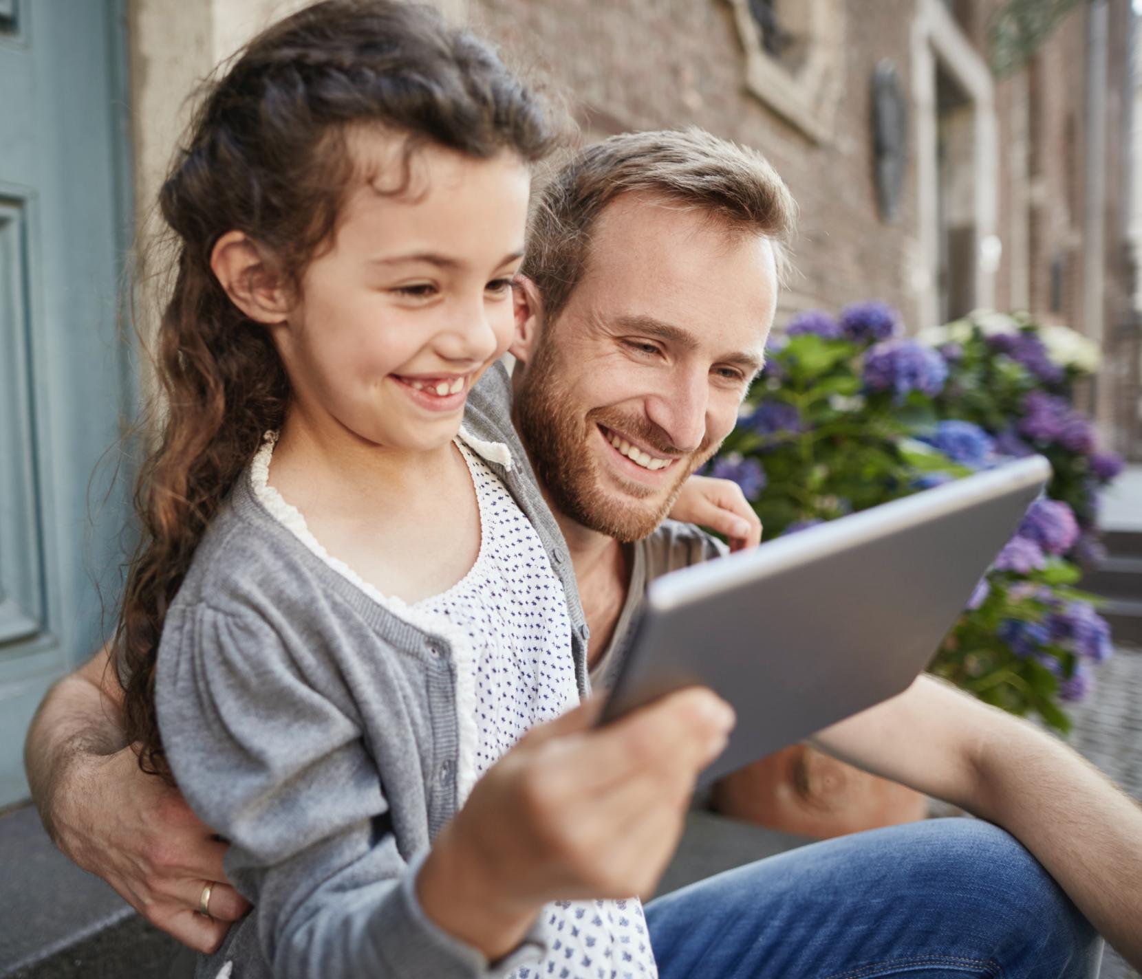 Daughter using a tablet outside next to her father